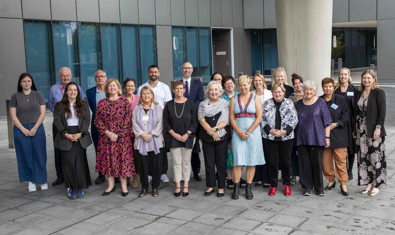 Members of the National Strategy Advisory Group and officials of the Attorney-General’s department are pictured standing in front of an office building. 